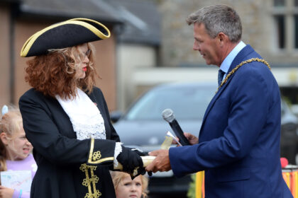 Town Crier Caroline Kolek hands the Honiton Market Charter scroll to Honiton Mayor Andrew Pearsall at the opening ceremony for Honiton Market Charter Day 2025 outside St Paul's Church.